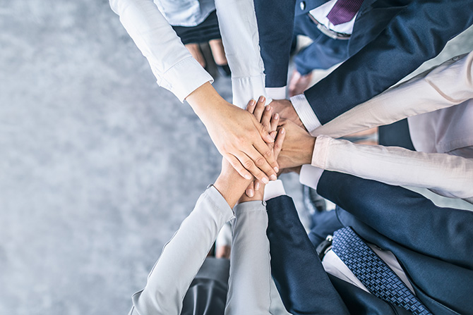 Group of professionals putting hands together in huddle