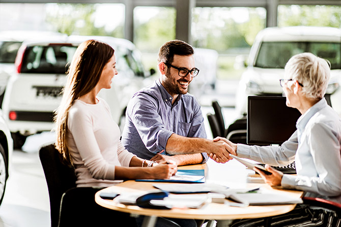 Couple shaking hands with auto dealer